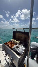 A well-equipped grill on a boat showcases delicious food being prepared, perfect for a fun day on the water.