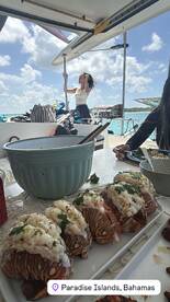 Guests enjoy a delicious lobster meal aboard a boat in Paradise Islands, Bahamas, showcasing the perfect blend of culinary delights and scenic views.