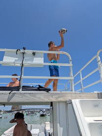 A fun moment on a boat as a young man prepares to throw a football while others relax nearby — perfect for a lively day on the water.