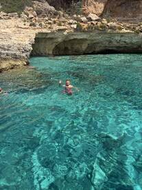 A man enjoys a refreshing swim in crystal-clear waters, surrounded by stunning rock formations — a perfect highlight of a day on the water.