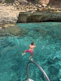 A person swims in crystal-clear waters near a rocky cave, showcasing the beauty of aquatic exploration and adventure.