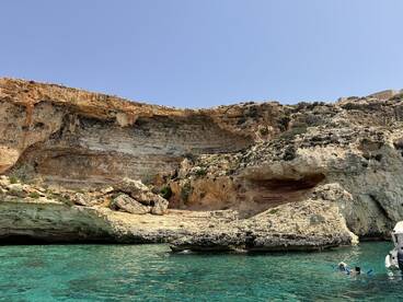 A stunning view of rocky cliffs and clear turquoise waters, showcasing the natural beauty of the coastline — perfect for exploring by boat.