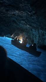 A group of adventurers kayaks through a stunning cave, illuminated by the blue waters, creating a magical atmosphere perfect for exploration.