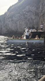 A lively group enjoys a boating adventure, capturing memories on the water with stunning rocky cliffs in the background.