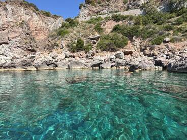 A stunning view of crystal-clear waters reflecting the rocky coastline, perfect for exploring hidden coves and enjoying nature's beauty.
