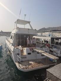A group of friends poses on the deck of a boat docked at the marina, showcasing a perfect day out on the water.
