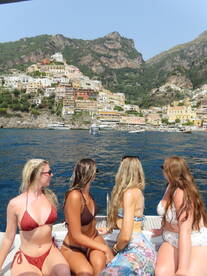 A group of friends enjoys a scenic boat ride along the stunning coastline of Positano, capturing the essence of a perfect summer getaway.