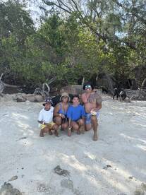 A joyful family poses together on the beach, capturing a memorable moment in a tropical paradise.
