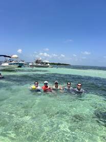 A lively group enjoys a sandbar stop, swimming in crystal-clear waters while surrounded by boats — a perfect day for fun and relaxation on the water.