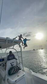 Two individuals leap off the boat into the water at sunset, capturing the essence of fun and adventure on the water.