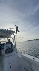 A child joyfully jumps off the side of a boat into the water, capturing the essence of fun and adventure on the water.