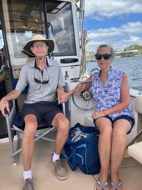 A couple relaxes inside the cabin of a boat, enjoying the view and the comfortable seating — perfect for a day on the water.