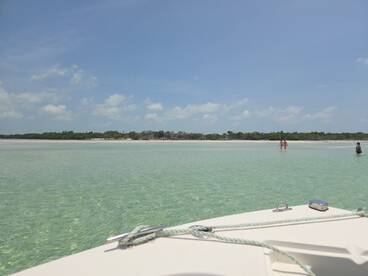 A scenic view from a boat at a sandbar, showcasing guests enjoying the shallow waters and sandy beach — a perfect spot for relaxation and fun in the sun.