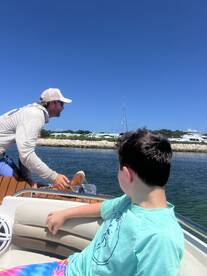 A man navigates a boat while a child looks on, capturing a moment of adventure on the water. Perfect for family outings and boating experiences.