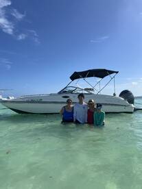 A family enjoys a fun day in the water next to their boat, creating lasting memories under the sun. Perfect for family outings and beach adventures.