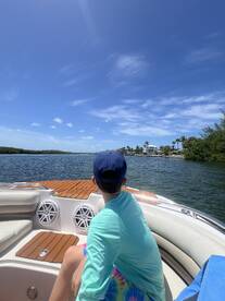 A young boy enjoys the scenic view from the boat, capturing the essence of a perfect day on the water surrounded by lush greenery and clear skies.