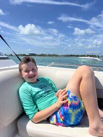 A cheerful child relaxes on a boat, enjoying a sunny day on the water — perfect for family outings and fun adventures.