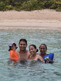 A joyful family enjoys a fun day swimming in clear waters, creating lasting memories at the beach.