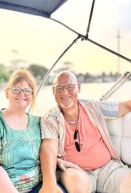 A smiling couple enjoys a relaxing moment on a boat, perfect for sunset cruises or romantic getaways on the water.