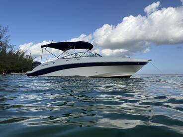 A sleek speedboat is anchored in calm waters, showcasing its elegant design against a backdrop of blue skies and fluffy clouds — perfect for a day on the water.