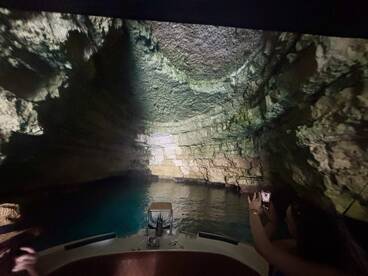 A captivating view of a cave's interior as a guest captures the moment on their phone while aboard a boat — a perfect blend of adventure and natural beauty.