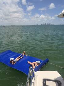 A fun day on the water with friends enjoying a floating mat while the stunning city skyline serves as a backdrop — perfect for summer adventures.