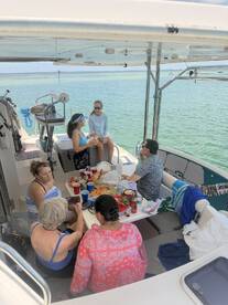 A lively group enjoys a meal and drinks aboard a boat, capturing the essence of a fun-filled day on the water with friends.