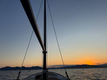 A stunning view of a sailboat's mast against a vibrant sunset, capturing the serene beauty of a sailing experience on calm waters.