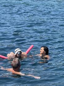A joyful moment in the water as a child enjoys swimming with family, showcasing fun and relaxation during a sunny day on the water.