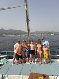 A joyful family poses together on the deck of a yacht, enjoying a sunny day on the water — perfect for memorable family outings and celebrations.