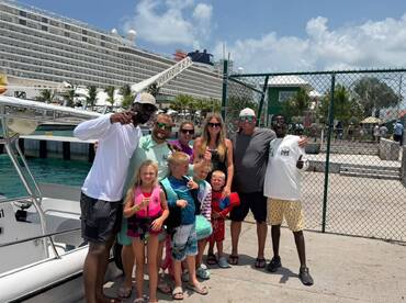 A joyful group of family and friends poses by their boat, ready for a fun-filled day on the water — perfect for family vacations and adventures.