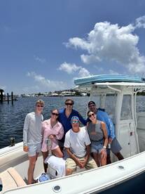A cheerful group poses for a photo aboard their boat, capturing a fun day on the water with friends and family.