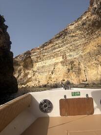 Interior view of a boat showcasing the seating area, with stunning rock formations visible in the background — perfect for exploring coastal landscapes.