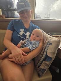 A mother holds her baby in the cozy cabin of a boat, showcasing a warm and intimate moment in a marine setting.