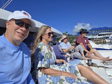 A cheerful group enjoys a sunny day on a boat, complete with a dog, showcasing the perfect family outing on the water.