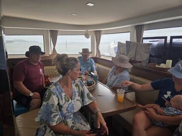 A cozy interior shot of a boat's cabin featuring a group of guests enjoying drinks and conversation, perfect for relaxing during a boating trip.