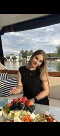A young woman enjoys a colorful fruit platter on a boat, perfect for a relaxing day on the water with delicious snacks.
