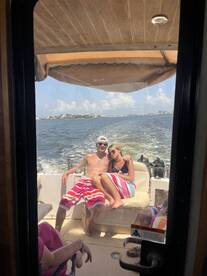 A couple enjoys a sunny day on a boat, wrapped in colorful towels, capturing the essence of a perfect summer outing on the water.