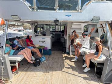 Guests relax inside the cabin of a boat, showcasing comfortable seating and a welcoming atmosphere for a day on the water.
