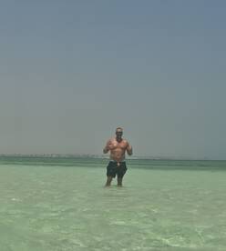 A man enjoys a refreshing swim in crystal-clear waters, showcasing the perfect beach day experience. Ideal for those seeking sun and fun on the water.