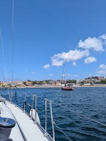 A scenic view of a yacht sailing along the coastline, showcasing beautiful waterfront properties and a clear blue sky — perfect for a day on the water.
