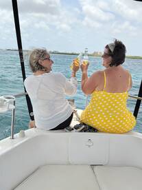 Two friends toast with cocktails while enjoying a sunny day on the boat, capturing the essence of friendship and celebration on the water.