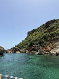 A stunning view of a rocky coastline with lush greenery and clear turquoise waters, perfect for exploring hidden coves and enjoying nature's beauty.