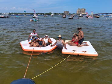 A lively group enjoys a day on the water, relaxing on floating mats while soaking up the sun — perfect for summer fun and social gatherings.