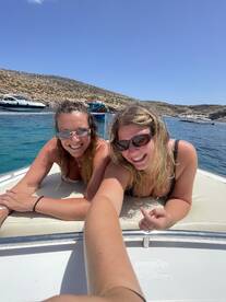 Two friends enjoy a sunny day on a boat, smiling and relaxing as they soak up the sun — a perfect moment for summer adventures on the water.