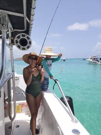 A woman and a child enjoy a fishing experience on a boat, showcasing their catch against a stunning ocean backdrop — perfect for family adventures on the water.