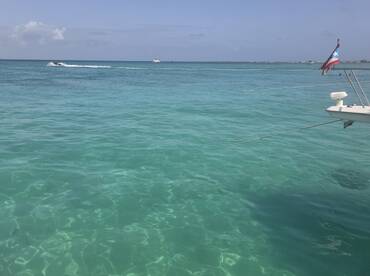 A serene view of a boat anchored in crystal-clear waters, showcasing the vibrant turquoise hues of the ocean — perfect for a relaxing day on the water.