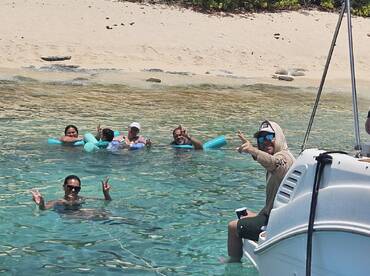 A lively group enjoys a refreshing swim in crystal-clear waters, showcasing the perfect beach day filled with fun and relaxation.