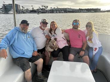 A cheerful group of friends enjoys a relaxing moment on a boat, accompanied by a dog, showcasing the joy of shared experiences on the water.