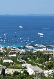 A stunning aerial view of a bustling harbor filled with various boats and yachts, showcasing the beautiful coastline and vibrant blue waters.